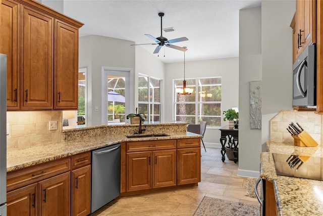 1254 Royal Pointe Ln, Ormond Beach, FL 32174 - kitchen with stainless steel dishwasher, brown cabinets, a ceiling fan, a peninsula, and decorative backsplash