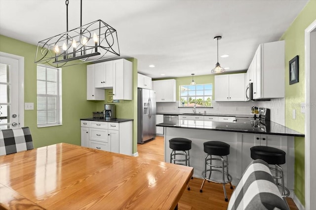 1026 Bel Aire Dr, Daytona Beach, FL 32118 - kitchen with stainless steel appliances, dark countertops, backsplash, light wood finished floors, and a chandelier