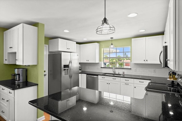 1026 Bel Aire Dr, Daytona Beach, FL 32118 - kitchen featuring appliances with stainless steel finishes, a peninsula, decorative backsplash, white cabinetry, and decorative light fixtures