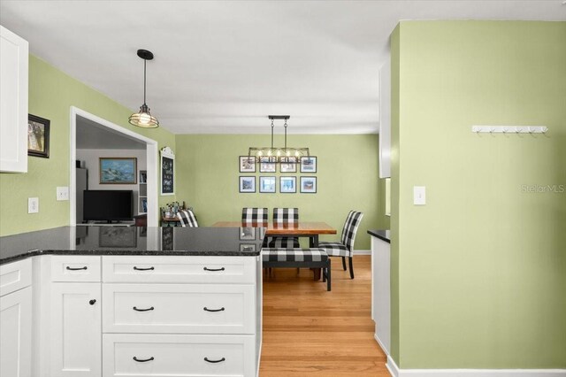 1026 Bel Aire Dr, Daytona Beach, FL 32118 - kitchen with a chandelier, a peninsula, white cabinets, and light wood finished floors