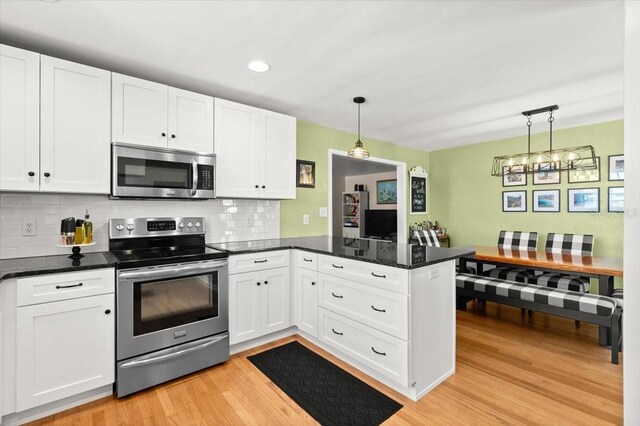 1026 Bel Aire Dr, Daytona Beach, FL 32118 - kitchen featuring stainless steel appliances, a peninsula, white cabinets, light wood finished floors, and recessed lighting