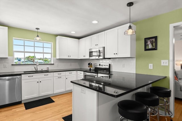 1026 Bel Aire Dr, Daytona Beach, FL 32118 - kitchen with stainless steel appliances, light wood-style flooring, white cabinets, backsplash, and recessed lighting