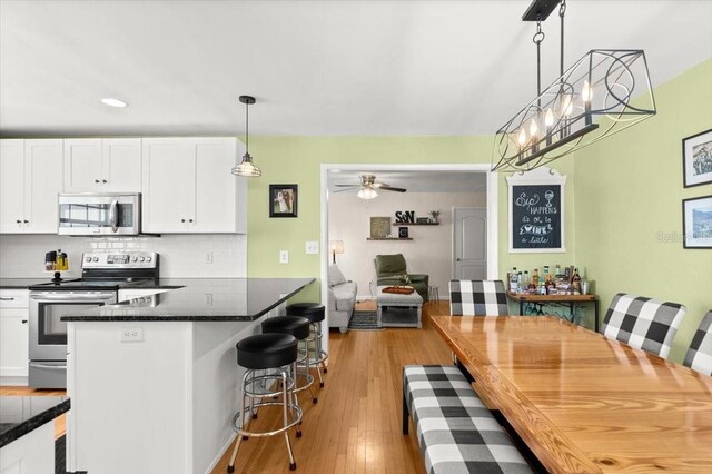 1026 Bel Aire Dr, Daytona Beach, FL 32118 - kitchen with appliances with stainless steel finishes, white cabinets, dark countertops, a breakfast bar, and backsplash