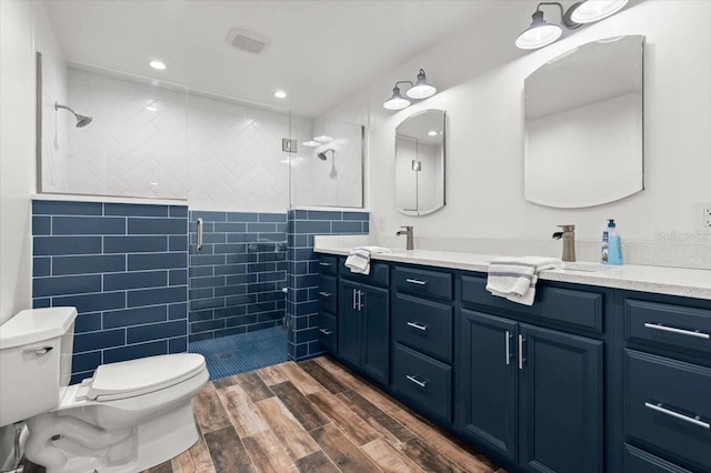1026 Bel Aire Dr, Daytona Beach, FL 32118 - full bathroom featuring a shower stall, double vanity, tile walls, wood finished floors, and recessed lighting