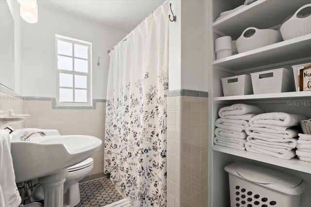 1026 Bel Aire Dr, Daytona Beach, FL 32118 - bathroom with tile walls, a wainscoted wall, and a shower with curtain
