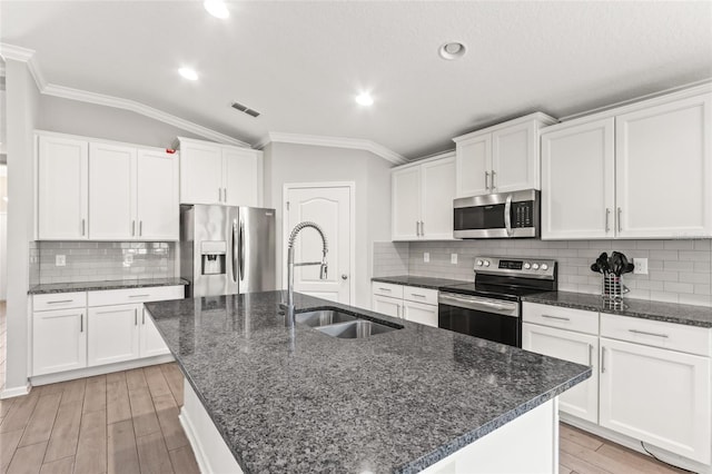 392 S Hamilton Springs Rd, Saint Augustine, FL 32084 - kitchen featuring appliances with stainless steel finishes, ornamental molding, vaulted ceiling, light wood-style flooring, and a kitchen island with sink