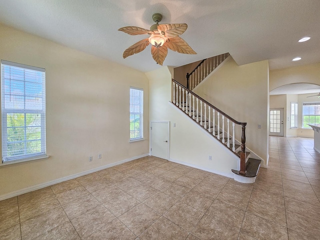 1528 N Daytona Ave, Flagler Beach, FL 32136 - unfurnished living room featuring ceiling fan, arched walkways, stairs, tile patterned flooring, and a textured ceiling
