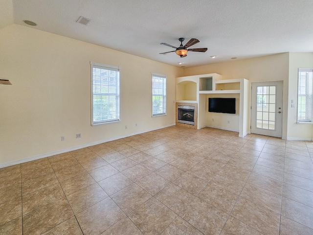 1528 N Daytona Ave, Flagler Beach, FL 32136 - unfurnished living room featuring light tile patterned floors, a tiled fireplace, ceiling fan, and built in shelves