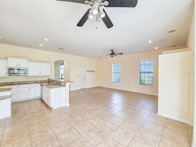 1528 N Daytona Ave, Flagler Beach, FL 32136 - kitchen featuring stainless steel microwave, a ceiling fan, arched walkways, a peninsula, and light tile patterned flooring
