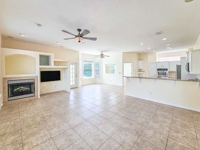 1528 N Daytona Ave, Flagler Beach, FL 32136 - unfurnished living room featuring light tile patterned floors, a ceiling fan, a tile fireplace, recessed lighting, and built in shelves