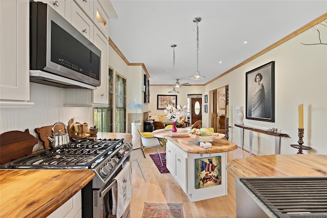 603 Front St, Welaka, FL 32193 - kitchen featuring stainless steel appliances, butcher block countertops, crown molding, and white cabinetry