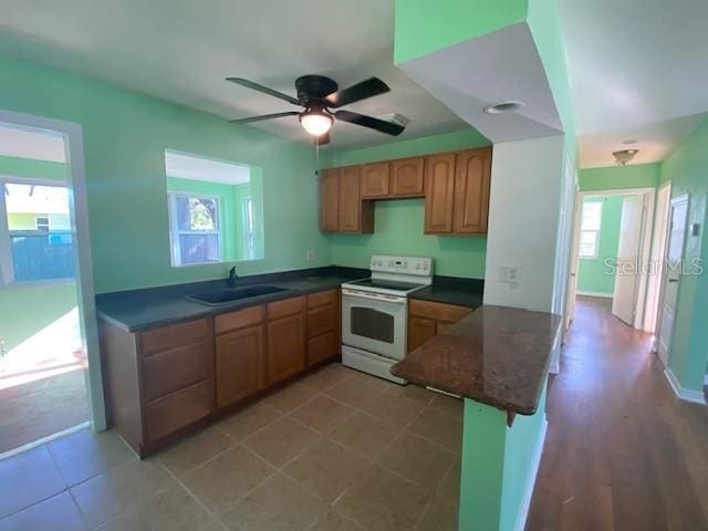 264 Sherwood Ln, Daytona Beach, FL 32117 - kitchen featuring white range with electric cooktop, a peninsula, dark countertops, ceiling fan, and a kitchen bar