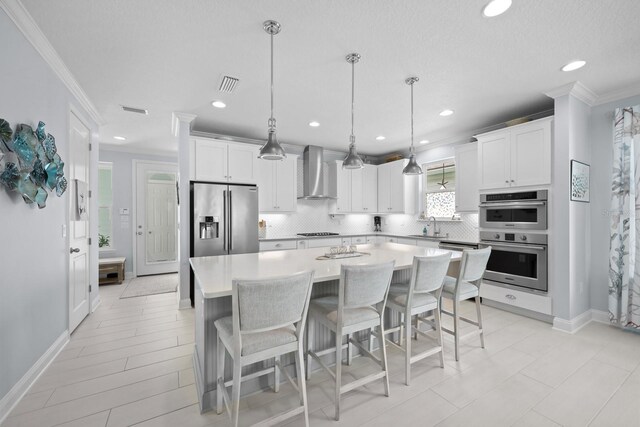 31 Hidden Treasure Dr, Palm Coast, FL 32137 - kitchen with stainless steel appliances, wall chimney exhaust hood, ornamental molding, tasteful backsplash, and a center island