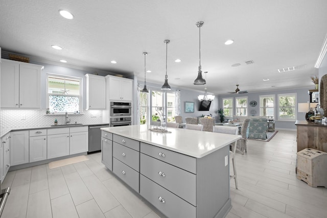 31 Hidden Treasure Dr, Palm Coast, FL 32137 - kitchen featuring appliances with stainless steel finishes, open floor plan, a center island, crown molding, and a ceiling fan