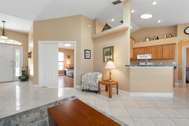 6 Prince Michael Ln, Palm Coast, FL 32164 - kitchen with white microwave, a peninsula, pendant lighting, high vaulted ceiling, and brown cabinetry