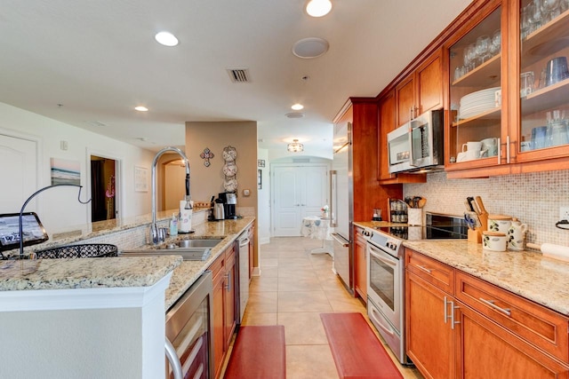 146 Palm Coast Resort Blvd Unit 501, Palm Coast, FL 32137 - kitchen with stainless steel appliances, brown cabinets, decorative backsplash, light tile patterned flooring, and light stone countertops