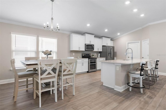 43 Lumber Jack Trl, Palm Coast, FL 32137 - kitchen featuring stainless steel appliances, a chandelier, ornamental molding, a center island with sink, and light wood-type flooring