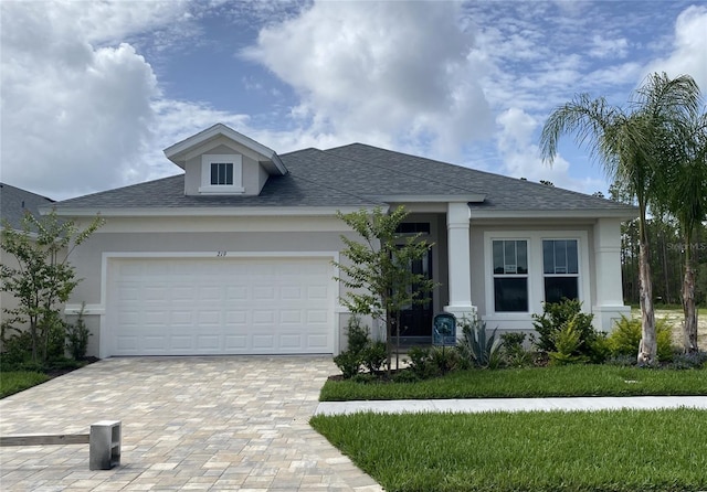 219 Hawthorn Ave, Palm Coast, FL 32164 - view of front facade featuring stucco siding, decorative driveway, an attached garage, and roof with shingles