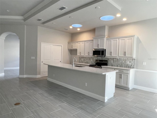 219 Hawthorn Ave, Palm Coast, FL 32164 - kitchen with stainless steel appliances, arched walkways, tasteful backsplash, an island with sink, and recessed lighting