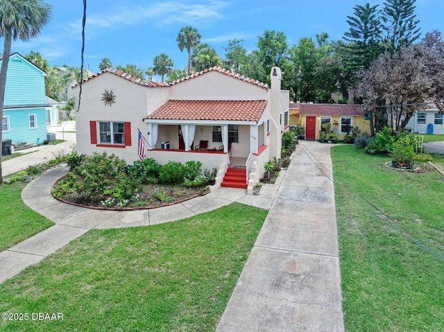 918 N Wild Olive Ave, Daytona Beach, FL 32118 - mediterranean / spanish house with a porch, stucco siding, a front lawn, and a tiled roof