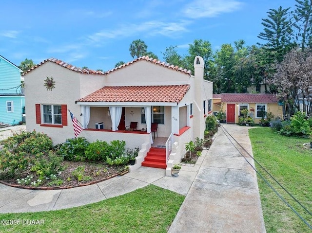 918 N Wild Olive Ave, Daytona Beach, FL 32118 - mediterranean / spanish house featuring a porch, a front yard, stucco siding, and a tiled roof