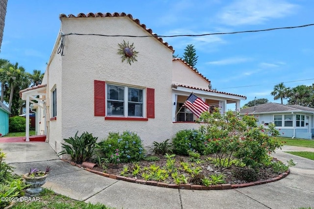 918 N Wild Olive Ave, Daytona Beach, FL 32118 - view of side of home featuring stucco siding and a tile roof