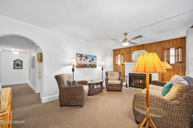 918 N Wild Olive Ave, Daytona Beach, FL 32118 - carpeted living area with arched walkways, wooden walls, a fireplace, and a ceiling fan