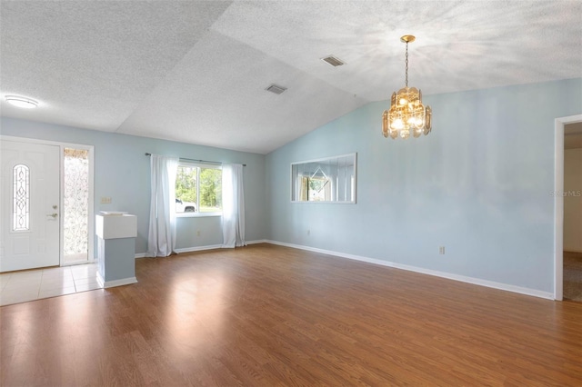 1 Wilson Pl, Palm Coast, FL 32164 - unfurnished living room featuring a chandelier, wood finished floors, vaulted ceiling, and a textured ceiling