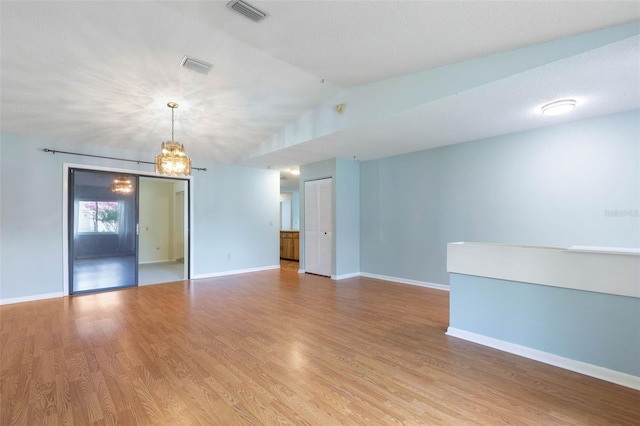 1 Wilson Pl, Palm Coast, FL 32164 - empty room with light wood finished floors, a chandelier, and vaulted ceiling