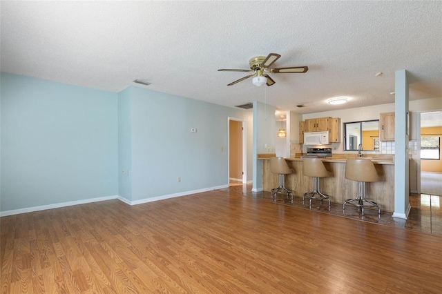 1 Wilson Pl, Palm Coast, FL 32164 - kitchen with white microwave, wood finished floors, a ceiling fan, a textured ceiling, and stove