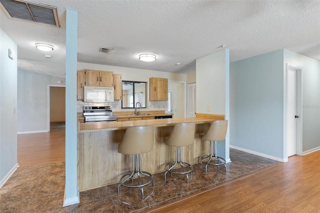 1 Wilson Pl, Palm Coast, FL 32164 - kitchen with white microwave, stainless steel electric stove, dark wood-type flooring, a kitchen bar, and a textured ceiling