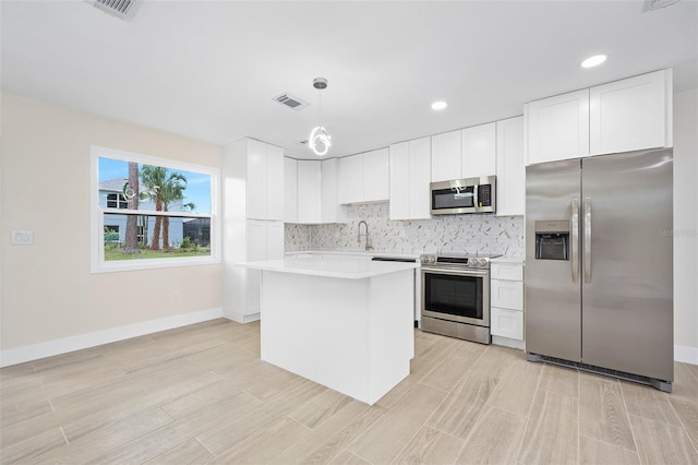 3 Fenwood Ln, Palm Coast, FL 32137 - kitchen featuring appliances with stainless steel finishes, light countertops, backsplash, a kitchen island, and white cabinets