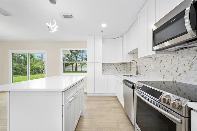 3 Fenwood Ln, Palm Coast, FL 32137 - kitchen featuring stainless steel appliances, light countertops, a kitchen island, backsplash, and white cabinets