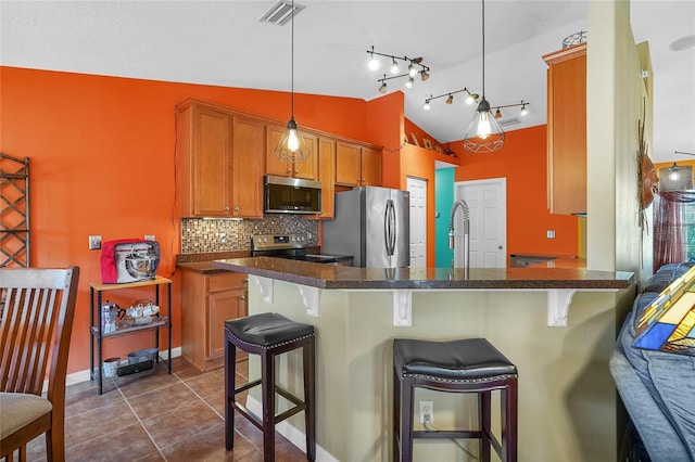 5 Zorlou Ct, Palm Coast, FL 32164 - kitchen featuring appliances with stainless steel finishes, lofted ceiling, dark countertops, backsplash, and a kitchen bar