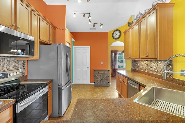 5 Zorlou Ct, Palm Coast, FL 32164 - kitchen featuring stainless steel appliances, dark countertops, light tile patterned floors, decorative backsplash, and arched walkways
