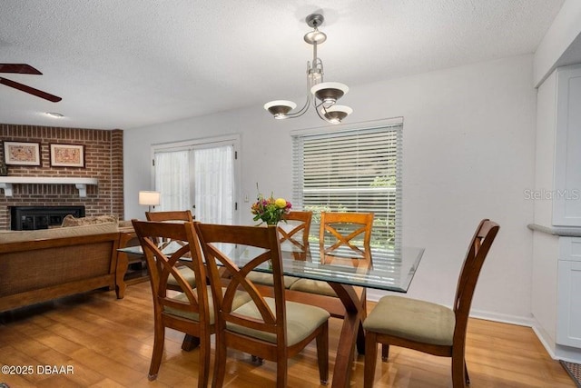 1108 Northside Dr, Ormond Beach, FL 32174 - dining area featuring a textured ceiling, ceiling fan, light wood-type flooring, a chandelier, and a brick fireplace