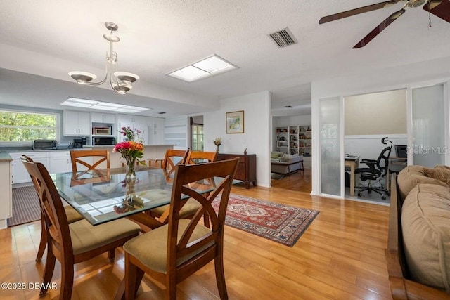 1108 Northside Dr, Ormond Beach, FL 32174 - dining room with light wood-style floors, a ceiling fan, a textured ceiling, and a chandelier
