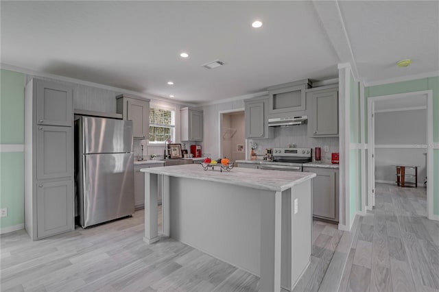 606 Ofarrell Ave, Interlachen, FL 32148 - kitchen featuring stainless steel appliances, gray cabinetry, under cabinet range hood, ornamental molding, and light wood-type flooring