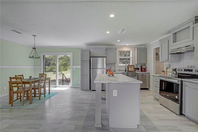 606 Ofarrell Ave, Interlachen, FL 32148 - kitchen featuring stainless steel appliances, gray cabinets, under cabinet range hood, a center island, and a breakfast bar area
