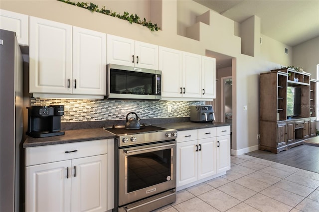 7 Lewis Shire Way, Palm Coast, FL 32137 - kitchen featuring appliances with stainless steel finishes, dark countertops, backsplash, light tile patterned flooring, and white cabinets