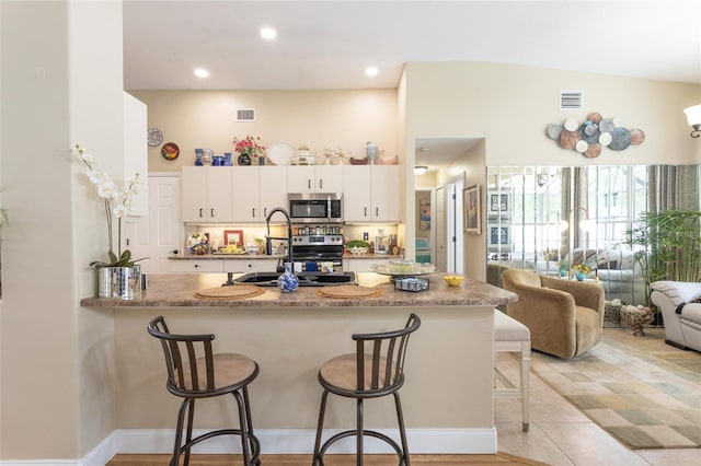 20 Long Pl, Palm Coast, FL 32137 - kitchen with appliances with stainless steel finishes, a peninsula, a kitchen bar, white cabinets, and recessed lighting