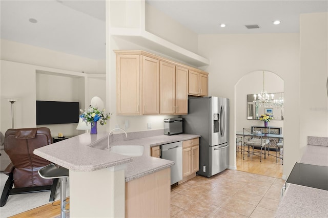 143 W Waterside Pkwy, Palm Coast, FL 32137 - kitchen with light brown cabinetry, appliances with stainless steel finishes, a chandelier, a peninsula, and open floor plan