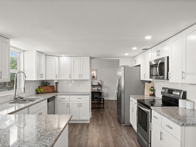 506 Dorset Cir S, Daytona, FL 32119 - kitchen with appliances with stainless steel finishes, backsplash, white cabinetry, a textured ceiling, and wood finished floors