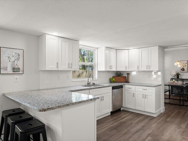 506 Dorset Cir S, Daytona, FL 32119 - kitchen with stainless steel dishwasher, a textured ceiling, a peninsula, white cabinets, and tasteful backsplash