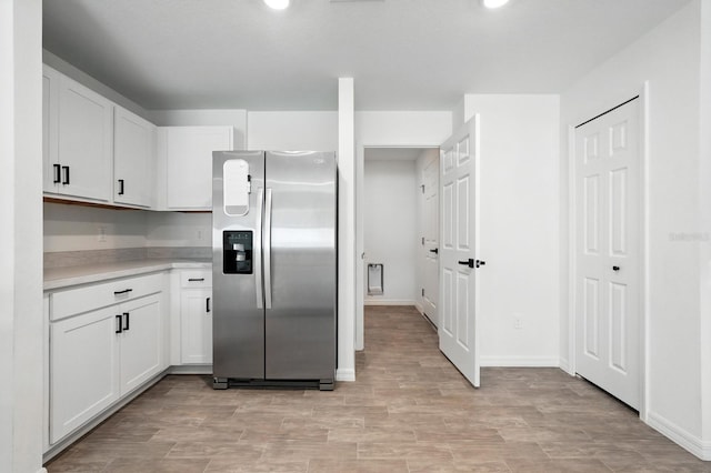 17 Roxbury Ln, Palm Coast, FL 32164 - kitchen with stainless steel fridge, light countertops, white cabinets, and light wood-style floors
