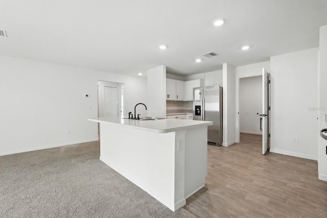 17 Roxbury Ln, Palm Coast, FL 32164 - kitchen with stainless steel fridge with ice dispenser, light countertops, white cabinetry, recessed lighting, and a center island with sink
