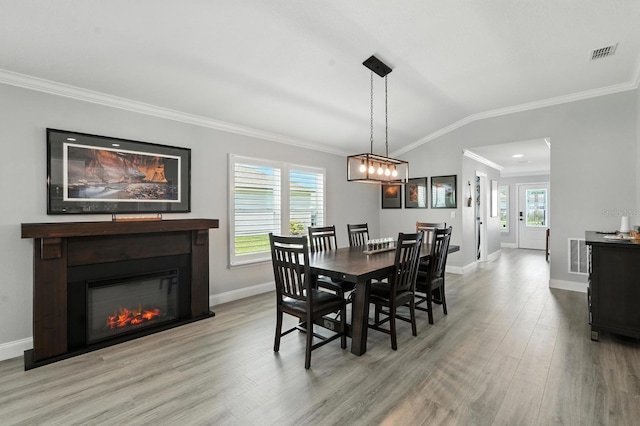 47 Lumberjack Trl, Palm Coast, FL 32137 - dining room with light wood-type flooring, crown molding, a glass covered fireplace, and lofted ceiling