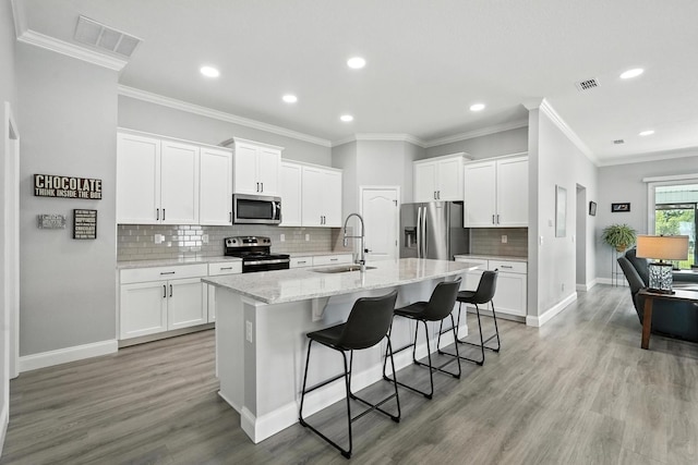 47 Lumberjack Trl, Palm Coast, FL 32137 - kitchen featuring stainless steel appliances, a kitchen island with sink, a breakfast bar, recessed lighting, and light wood-style flooring