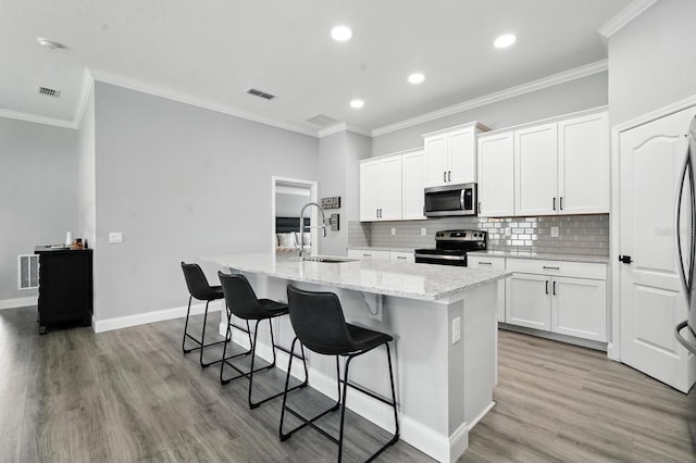 47 Lumberjack Trl, Palm Coast, FL 32137 - kitchen with appliances with stainless steel finishes, light wood finished floors, an island with sink, decorative backsplash, and recessed lighting