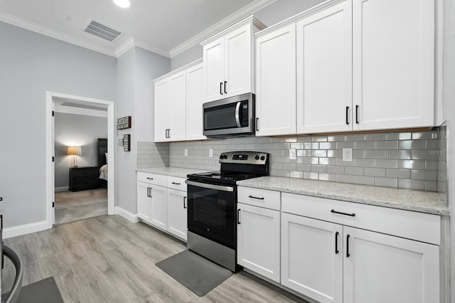 47 Lumberjack Trl, Palm Coast, FL 32137 - kitchen with stainless steel appliances, ornamental molding, light wood-style flooring, white cabinetry, and decorative backsplash